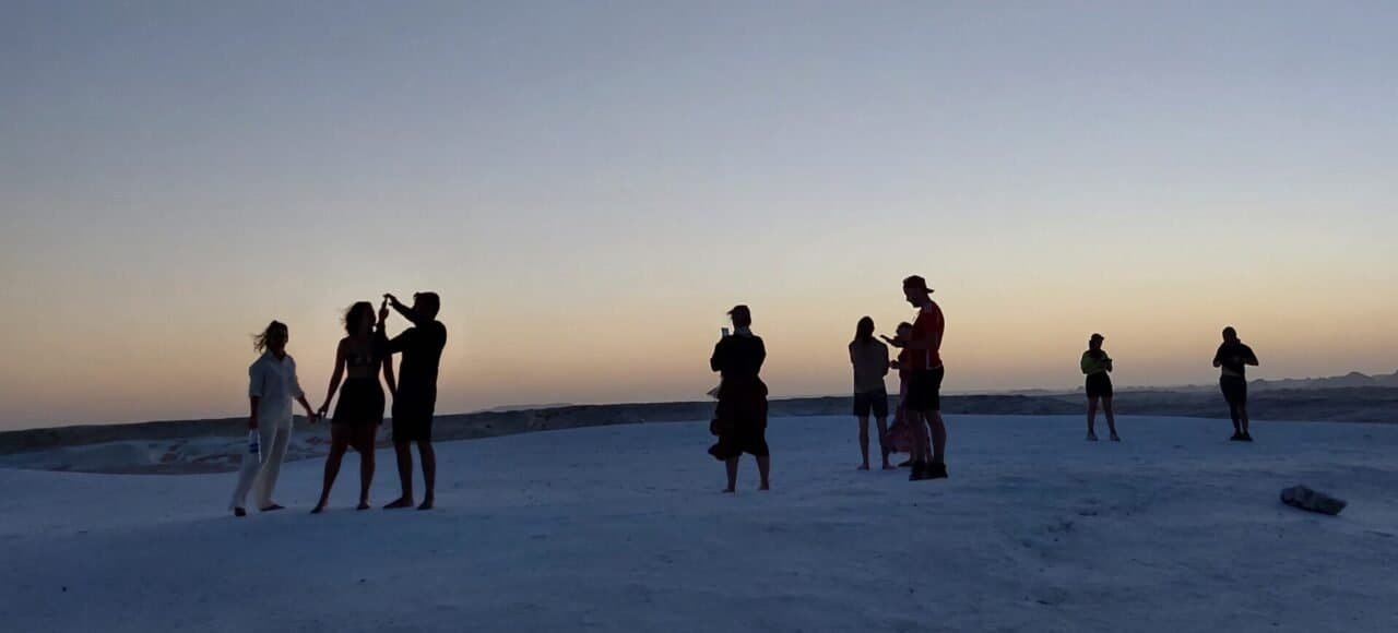 Travellers silhouetted on the White Desert at dusk