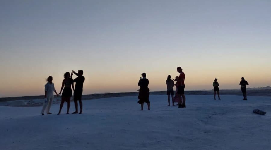 Travellers silhouetted on the White Desert at dusk