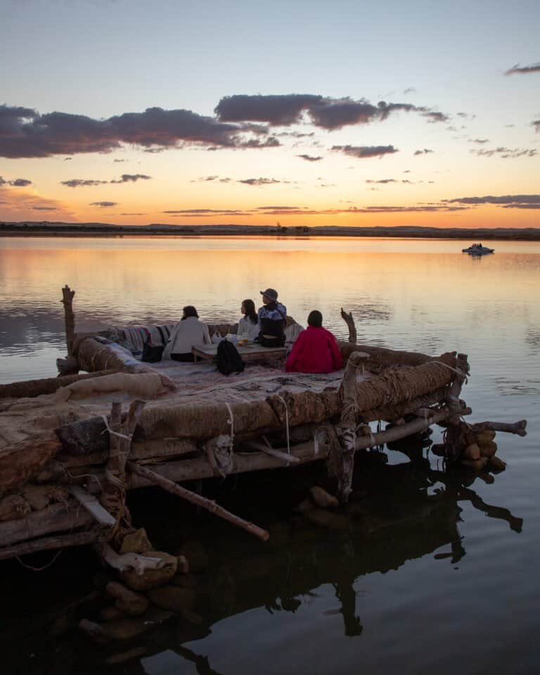 Travellers on a wooden pier at sunset over a Siwa salt lake