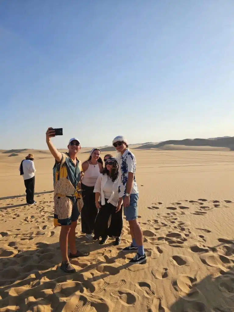 Travellers taking photos on the dunes during a Siwa desert safari