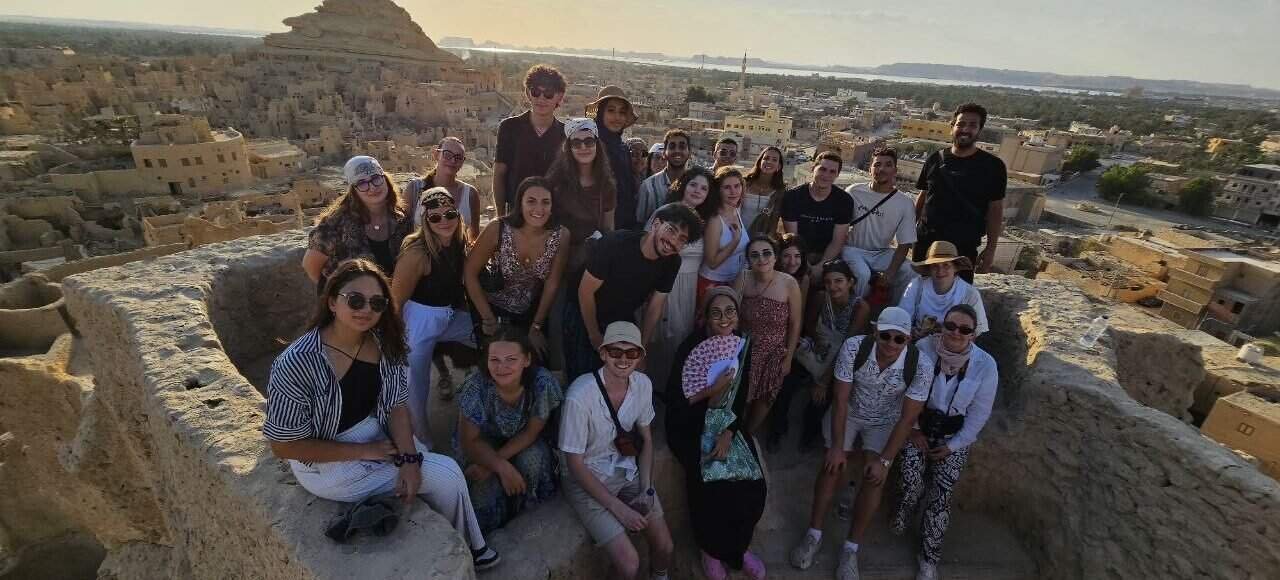 Group of travellers on a rocky hilltop in Siwa at sunset