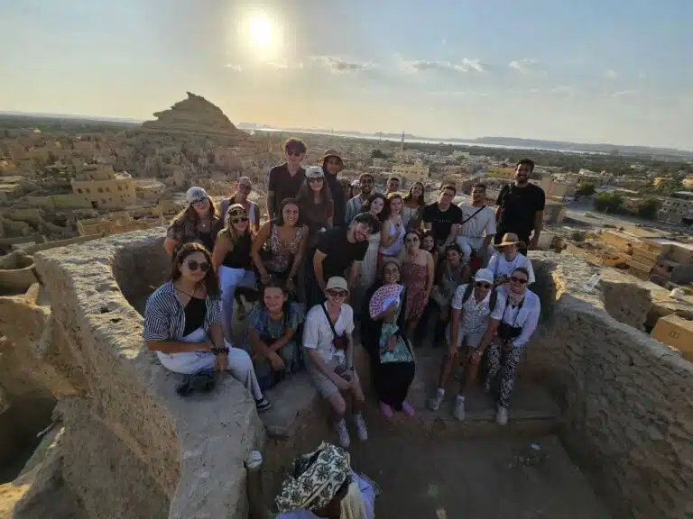 Group of travellers on a rocky hilltop in Siwa at sunset