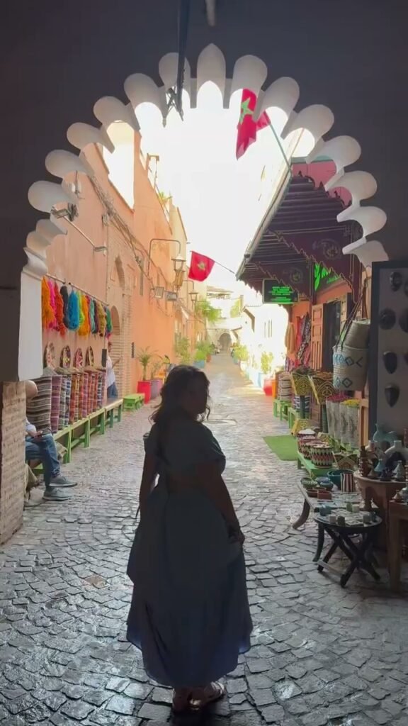 Traveller walking through a colourful medina alley lined with rugs and woven baskets in Morocco