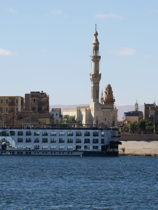 Nile cruise ship sailing past a mosque on the riverbank in Aswan
