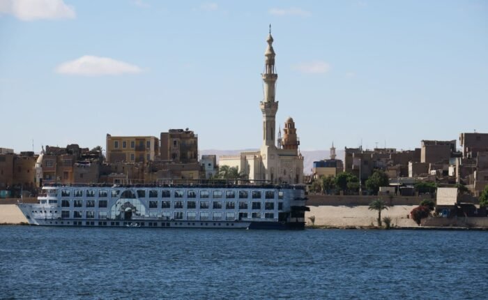 Nile cruise ship sailing past a mosque on the riverbank in Aswan