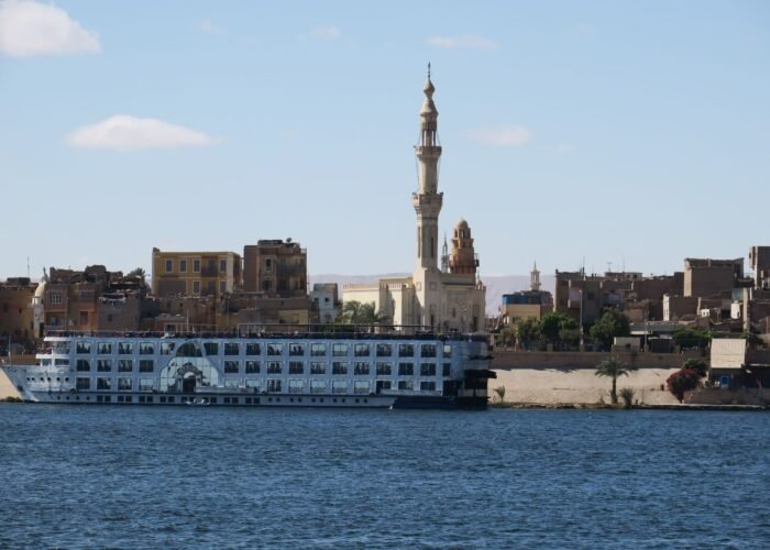 Nile cruise ship sailing past a mosque on the riverbank in Aswan